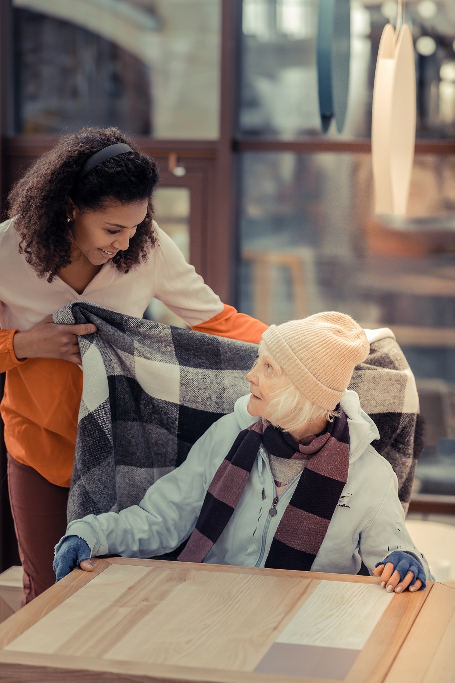 Caregiver covering elderly woman with a blanket