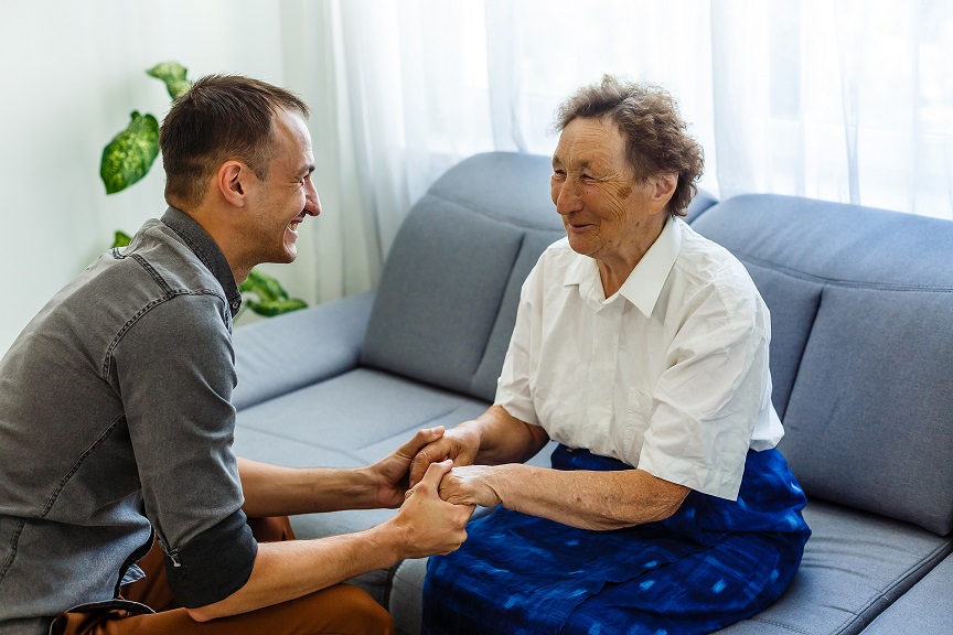 Young caregiver holding elderly woman by the hands